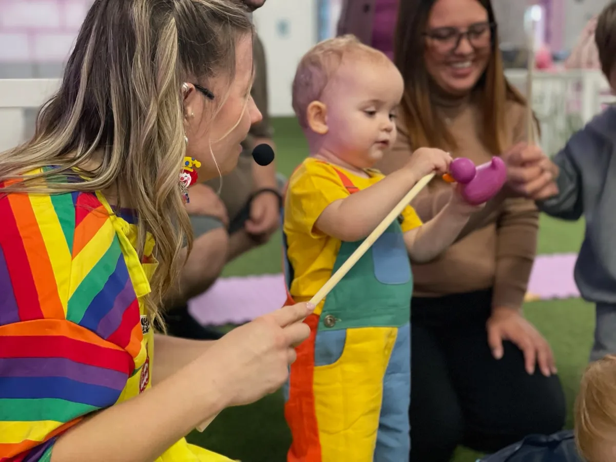 Coralie in her rainbow outfit playing a fishing game with a toddler at a party
